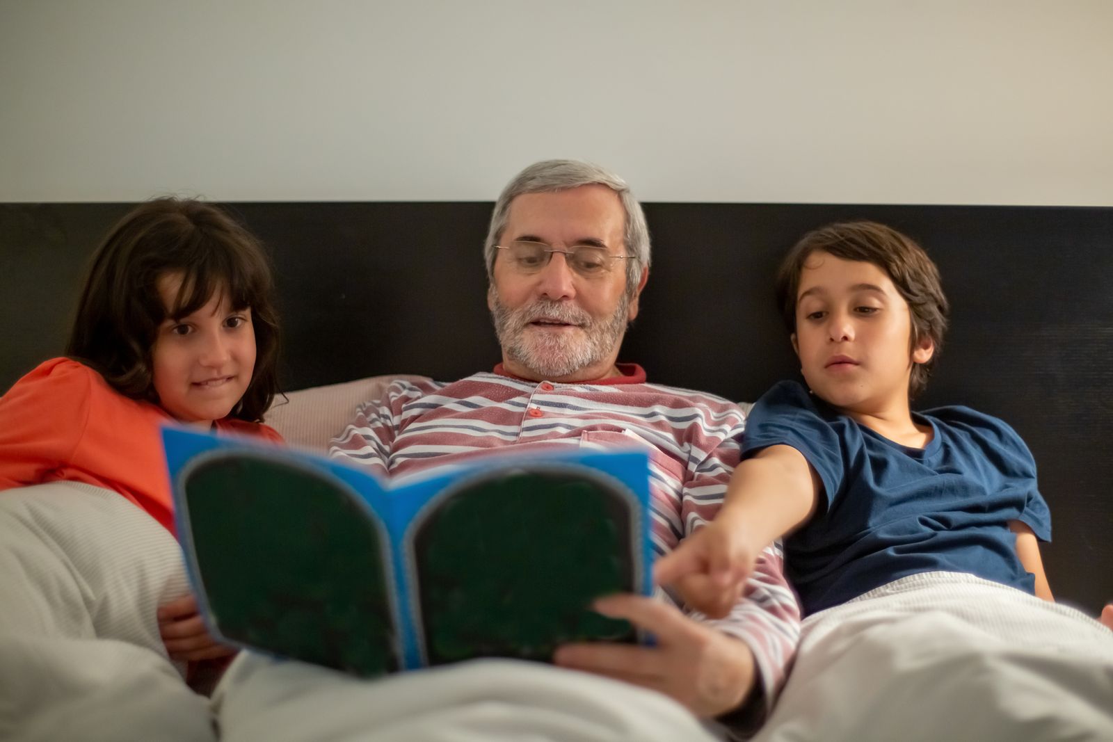Grand-père qui lit un livre avec ses petits-enfants